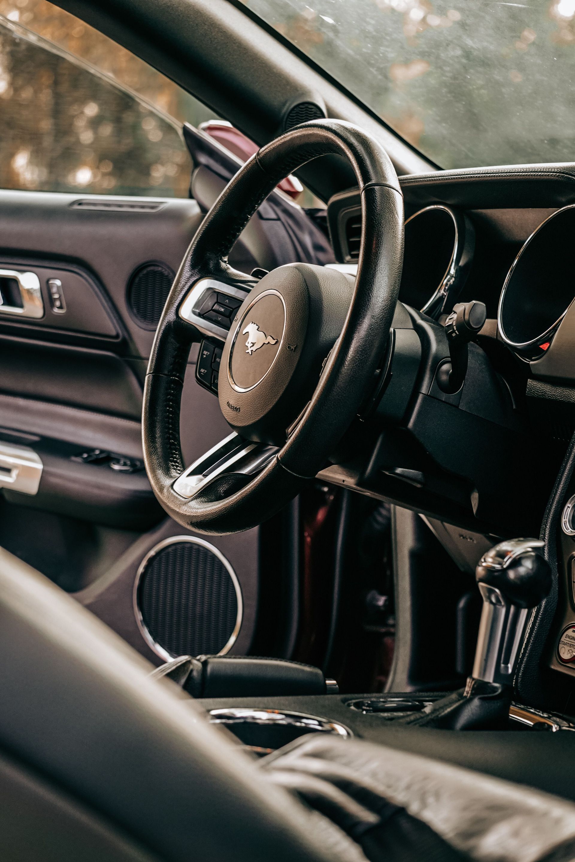 Elegant car interior featuring a leather steering wheel and gear shift in a classic auto.
