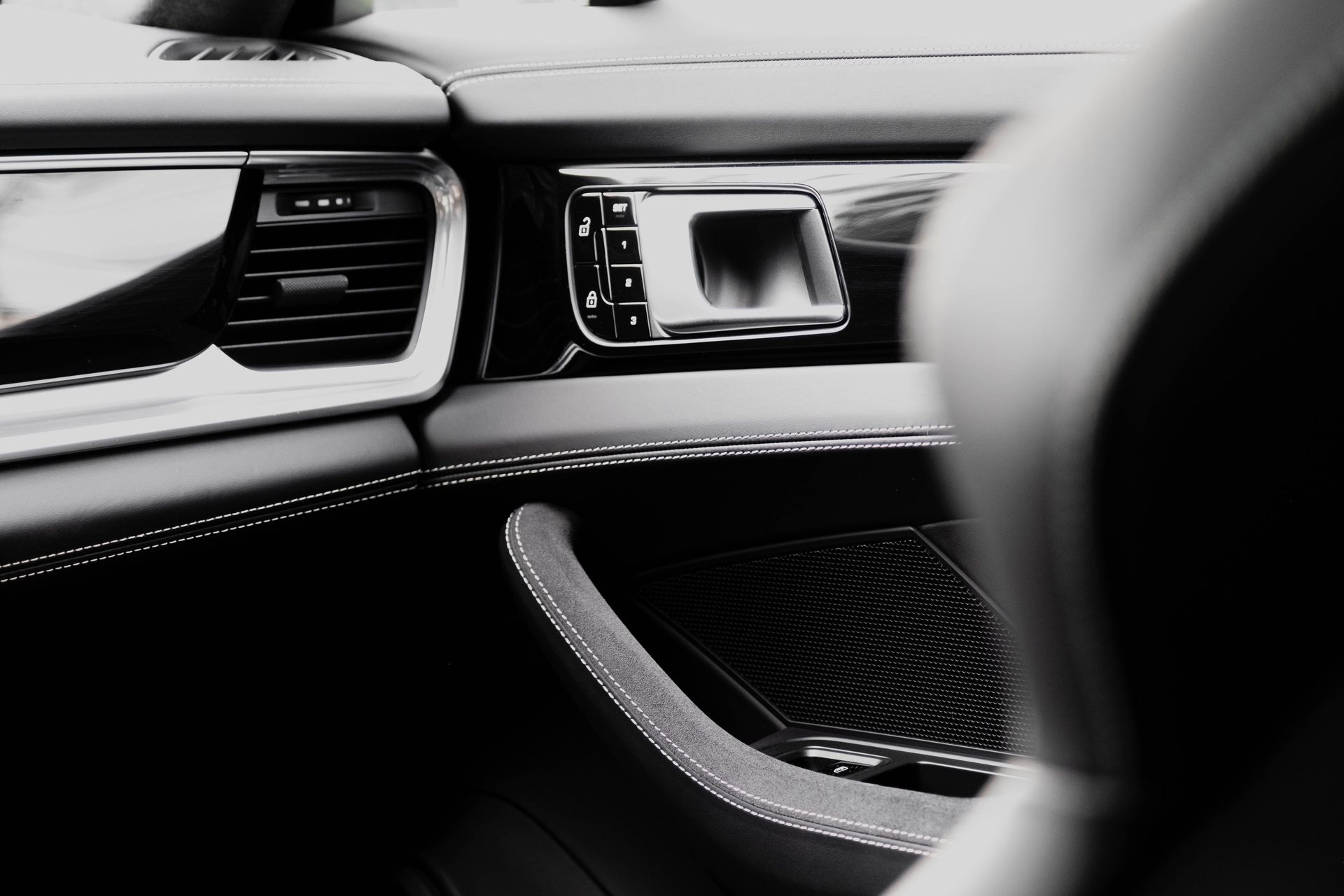Close-up of a luxury car interior with a focus on the sleek dashboard and leather stitching.