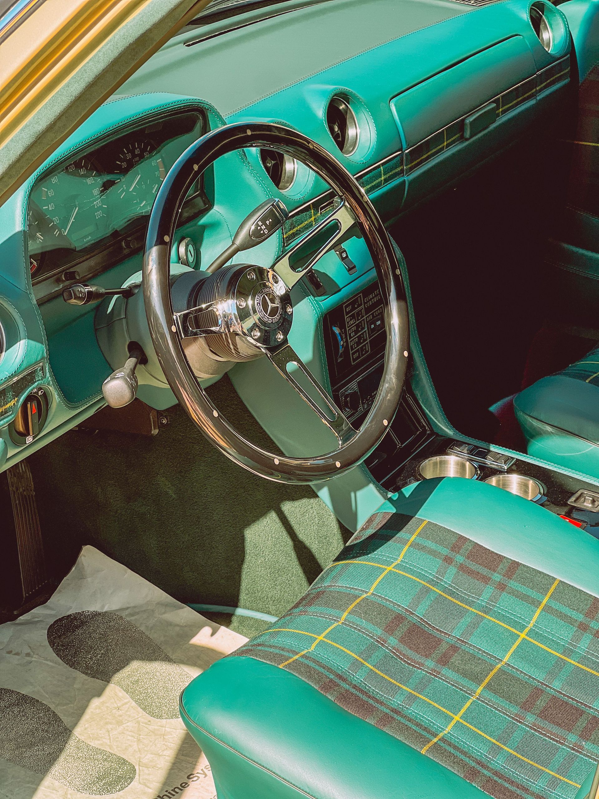 Classic car interior with vibrant green dashboard and plaid seats, showcasing retro design.